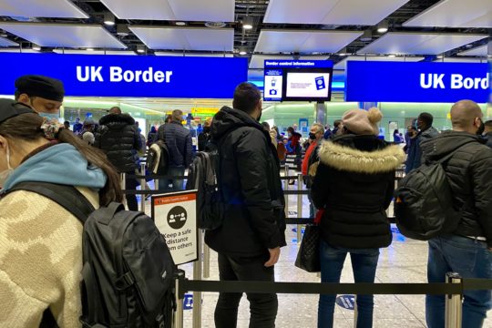 Air travelers queue at border control at Heathrow Airport.