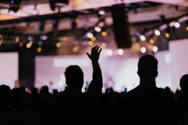 Shows outline of people at a conference or event with bright lights in the background